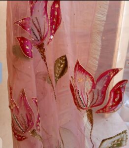 Light pink organza dupatta with hand-painted red and pink floral designs, decorated with gold detailing and beads.