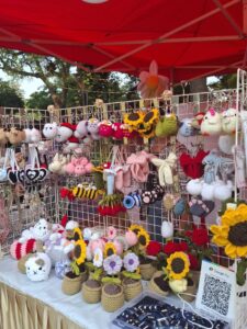 Crochet handmade accessories hanging on display racks at a vendor booth.